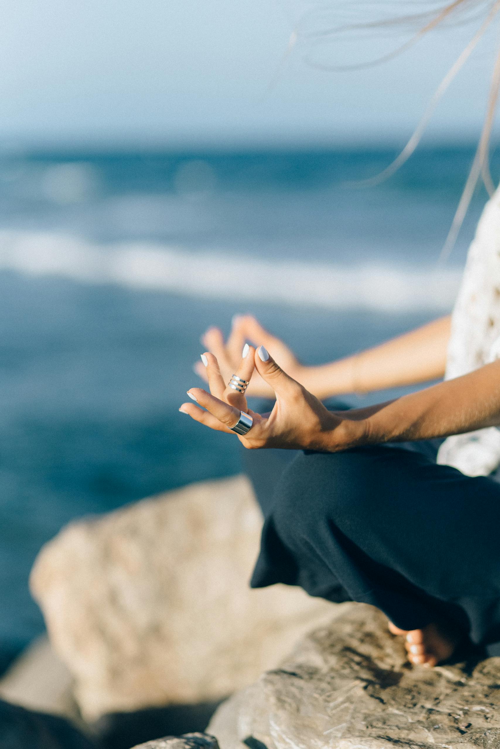 Close-up of a person meditating by the seaside, capturing tranquility and balance.